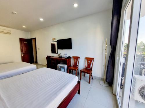 een slaapkamer met 2 bedden, een bureau en een televisie bij Minh Khue Hotel in Vĩnh Long