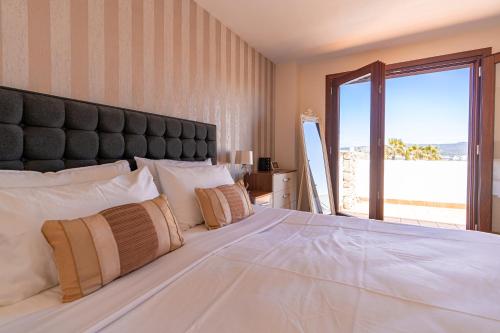 a bedroom with a large white bed with a large window at Beautiful Villa Bohemia Ibiza in Sant Josep de Sa Talaia