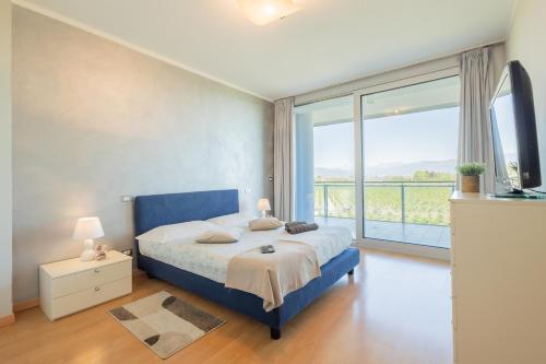 a bedroom with a blue bed and a large window at Glass House in Cuneo