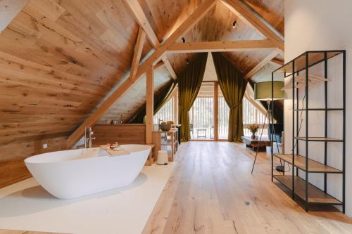 baño con bañera blanca grande y techos de madera. en PIRA HOTEL, en Postojna