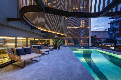 Best Western Ratchada Hotel في بانكوك: مسبح وكراسي صالة ومبنى