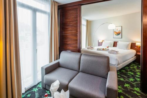 a hotel room with a bed and a couch at Mercure Lourdes Impérial in Lourdes