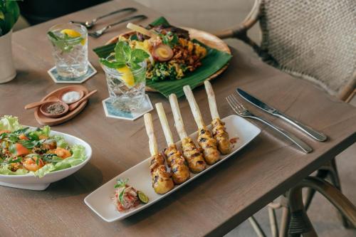 une table avec des assiettes de denrées alimentaires et des assiettes de denrées alimentaires dans l'établissement Kanvaz Village Resort Seminyak, à Seminyak