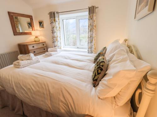 a large white bed in a room with a window at Rawfell in Ambleside