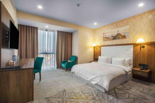 a hotel room with a large bed and a desk at Royal Tulip Hotel & Casino, Tbilisi in Tbilisi City