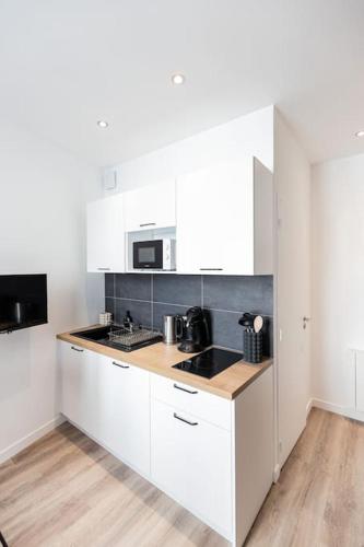 une cuisine avec des armoires blanches et un micro-ondes dans l'établissement Le doux nid - Résidence Hestia, à Saint-Étienne