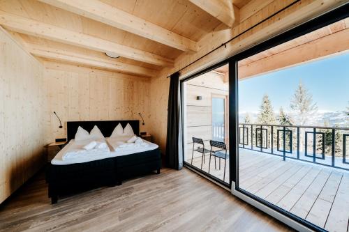 a bedroom with a bed and a balcony at Clofers Active Apartments Sonnleitn in Hermagor