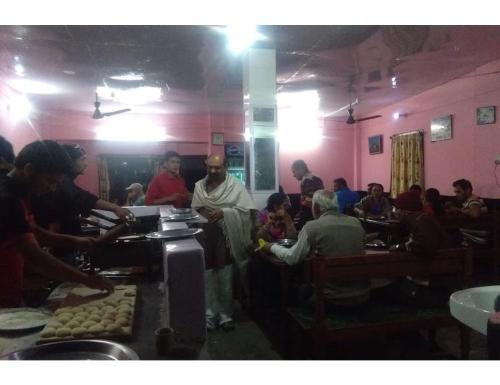 un gruppo di persone sedute in un ristorante che mangiano cibo di Raj Palace, Uttarkashi a Uttarkāshi