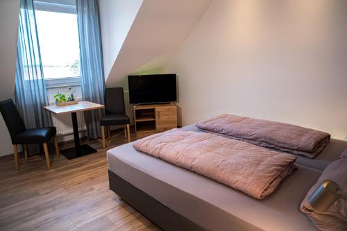 a bedroom with a bed and a desk and a television at Gästezimmer Düll in Dettelbach