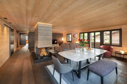 a living room with a table and a fireplace at Swiss Hotel Apartments - Gstaad in Gstaad