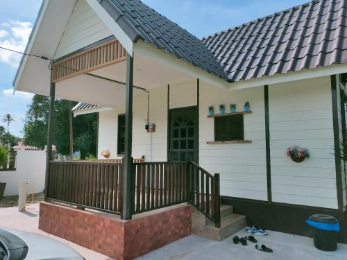 een huis met een veranda met een dak bij Sue Cottage Homestay in Jertih