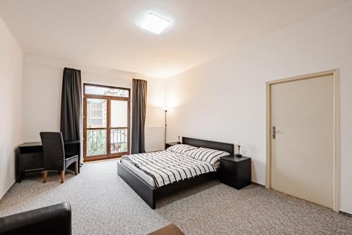 1 dormitorio con cama, escritorio y ventana en REZIDENCE PODĚBRADY, en Poděbrady
