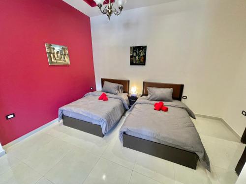two beds in a room with a red wall at Villa Mira GuestHouse 2 - Downtown Central Amman - AL DIYRIH in Amman