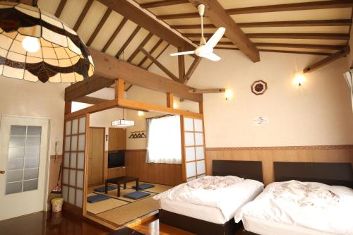 two beds in a room with wooden ceilings at Tennenonsen Amuri in Amakusa