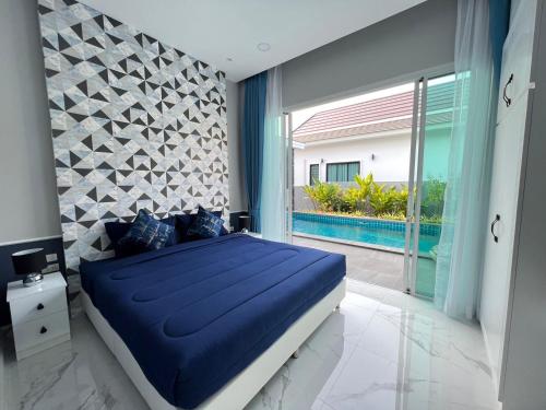 a bedroom with a blue bed and a large window at Aranya pool villa in Ban Phu Yai