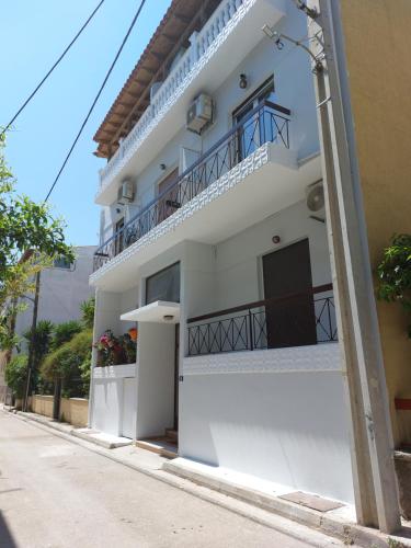 a white building with a balcony on a street at Crystal Home near Airport in Artemida