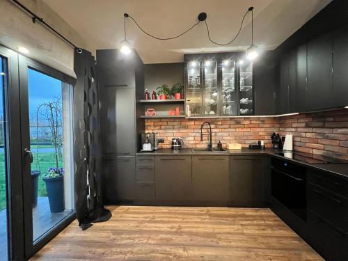 a kitchen with black cabinets and a brick wall at Silesia Apartments B129 in Ustroń