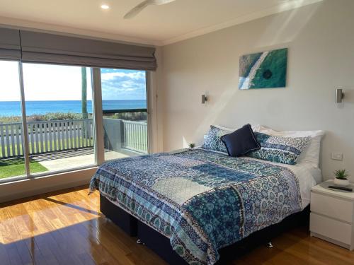 a bedroom with a bed with a view of the ocean at THE DECK HOUSE - Beautiful Busselton Beachfront in Busselton