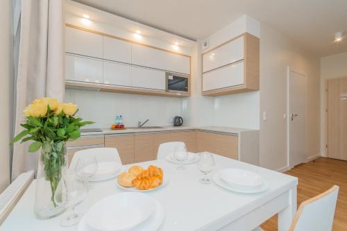 a kitchen with a white table with a vase of flowers at Apartamenty NCNK Marina Kąty Rybackie in Kąty Rybackie