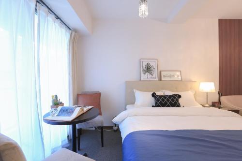a bedroom with two beds and a table and a window at LEOPARD Shinsaibashi in Osaka