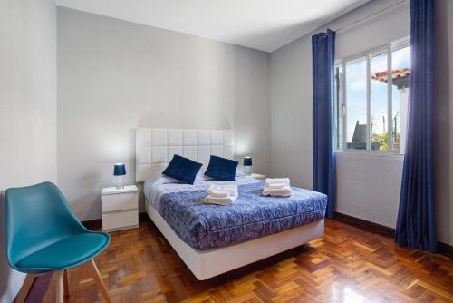 Un dormitorio con una cama y una silla azul. en Estrela House, en Venda do Atalhinho