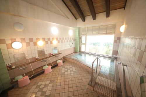 a bathroom with a tub and a sink and a mirror at Tennenonsen Amuri in Amakusa