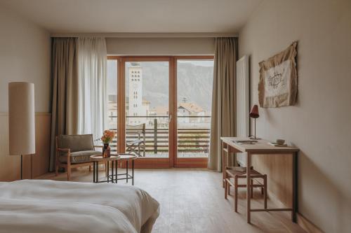 ラーナにあるHotel Schwarzschmiedのベッド、デスク、窓が備わるホテルルームです。
