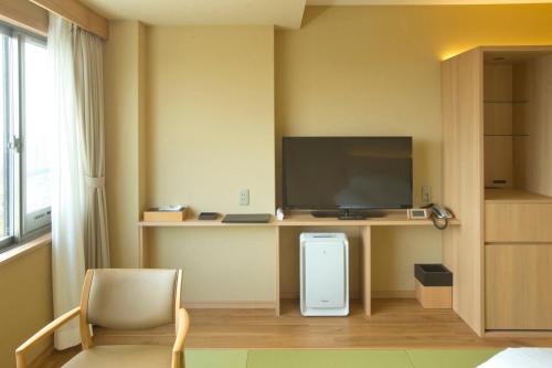a room with a tv and a desk with a chair at 山荘 風の杜 Sanso Kazenomori in Minoo
