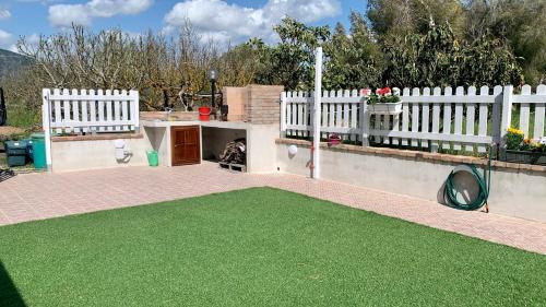 podwórko z białym płotem i zieloną trawą w obiekcie Elvira Casa Vacanze w mieście Iglesias