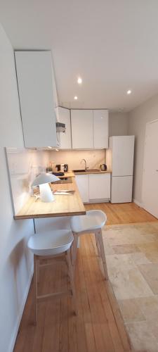 une cuisine avec une table et deux chaises blanches dans l'établissement Royan appartement centre ville/mer, à Royan