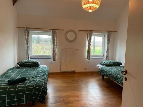 two beds in a room with two windows at Cottage entier : 6 à 8 personnes - La Ferme du Try in Frasnes-lez-Gosselies