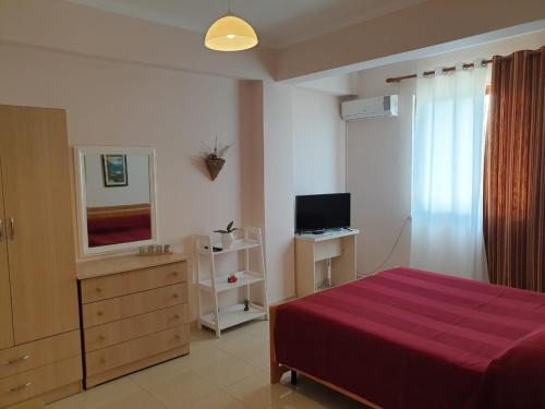 een slaapkamer met een rood bed en een televisie bij Jozi Kaiser Apartment 3 in Durrës