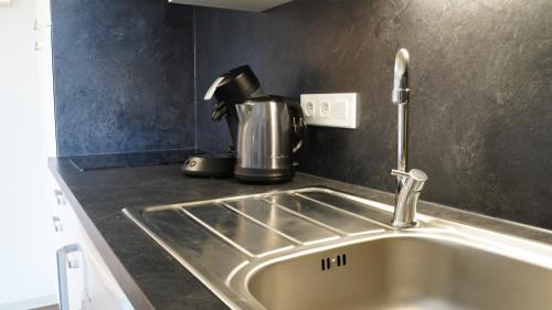 a kitchen counter with a sink and a coffee pot at Apparts Confort 87 in Limoges