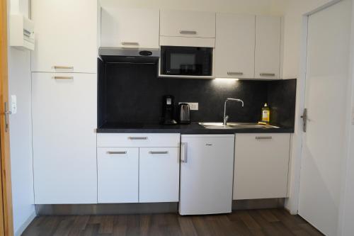a white kitchen with white cabinets and a sink at Apparts Confort 87 in Limoges