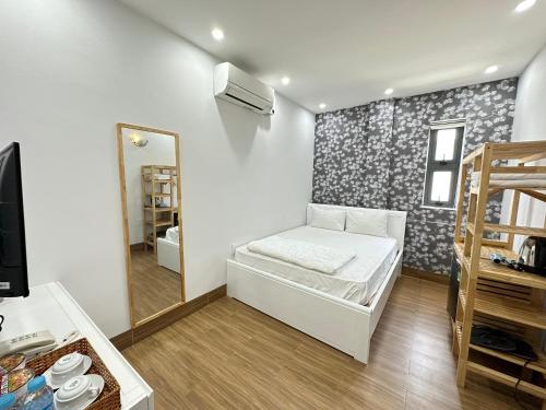 a small room with a bed and a mirror at The Land Hotel & Apartment in Vung Tau
