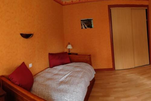 1 dormitorio con 1 cama con almohadas rojas y puerta en Maison entière 3 chambres, en Saint-Brevin-les-Pins