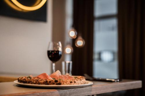 a pizza on a table with a glass of wine at Hotell Kramm in Kramfors
