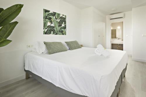 ein weißes Bett in einem weißen Schlafzimmer mit einer Pflanze in der Unterkunft Perfect apartment 3 - TCM in Fuengirola