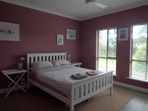 a bedroom with a white bed and two windows at Blue Wren Studio Apartment in Currency Creek