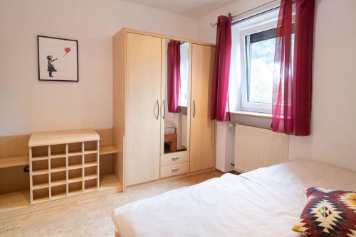 a bedroom with a bed and a window with red curtains at Ferienwohnung Am Eichholz in Coburg