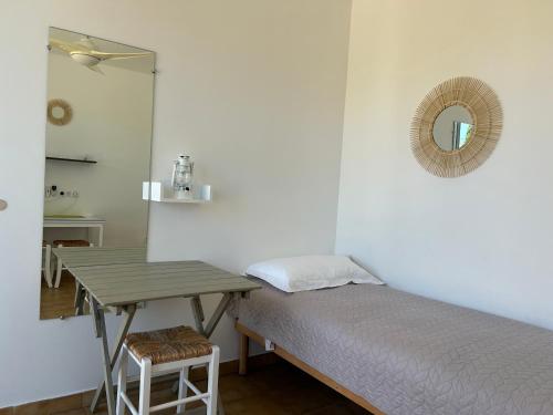 a bedroom with a bed and a table and a mirror at Hôtel Punta e Mare des Chambres ou des Appartements T2 in Cargèse