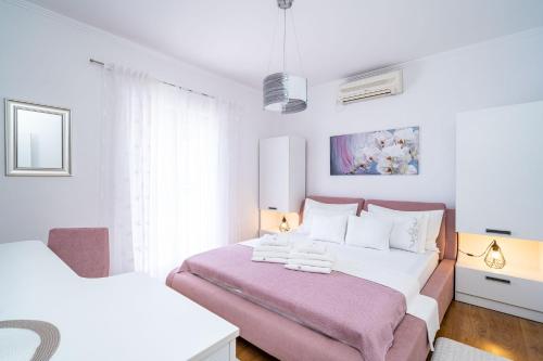 Apartment & Rooms Duja في زاتون: غرفة نوم بيضاء بسريرين وبطانية وردية