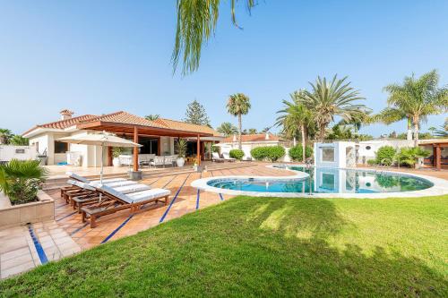 a backyard with a swimming pool and a house at Luxury Villa Maspalomas Golf in Maspalomas