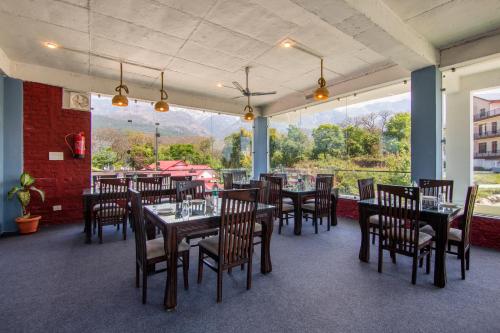 a restaurant with tables and chairs and a large window at Treebo Ortus Residency in Dharamshala