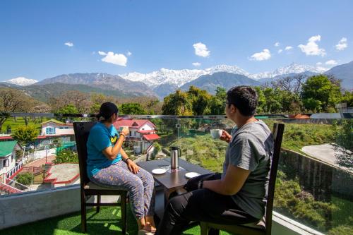 two people sitting at a table with a view of mountains at Treebo Ortus Residency in Dharamshala