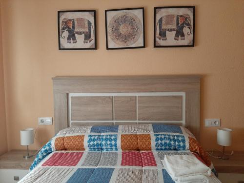 um quarto com uma cama com quatro fotografias na parede em Peña del Castillo em La Iruela