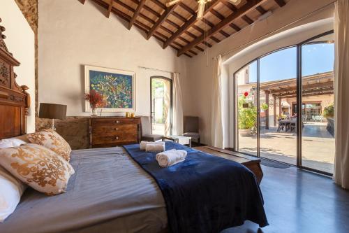 um quarto com uma cama grande e uma janela grande em Masia Notari Casabona em Vilanova i la Geltrú