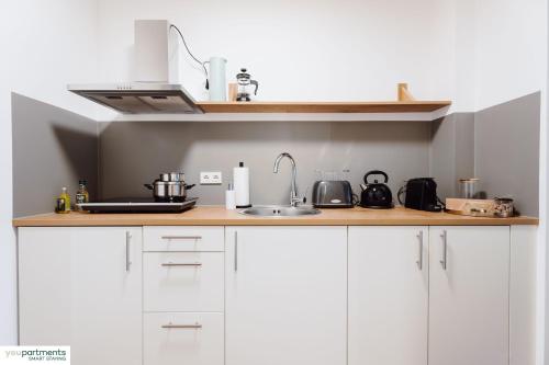 una cocina con armarios blancos y fregadero en City-Studio mit Boxspring-Bett und Küche en Münster