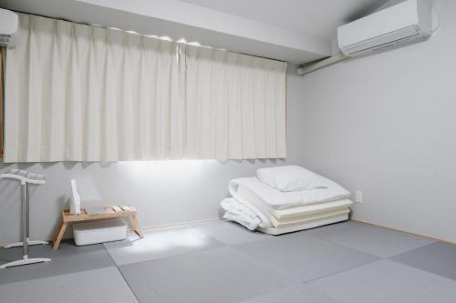 Cette chambre blanche comprend un lit et une table. dans l'établissement 自由自屋, à Nachikatsuura