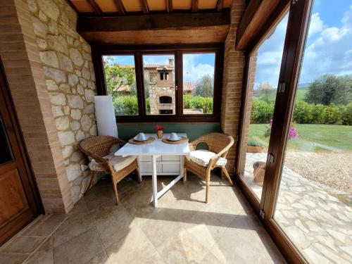 eine Terrasse mit einem Tisch, Stühlen und einem Fenster in der Unterkunft Podere San Luigi - Pet Friendly in Volterra